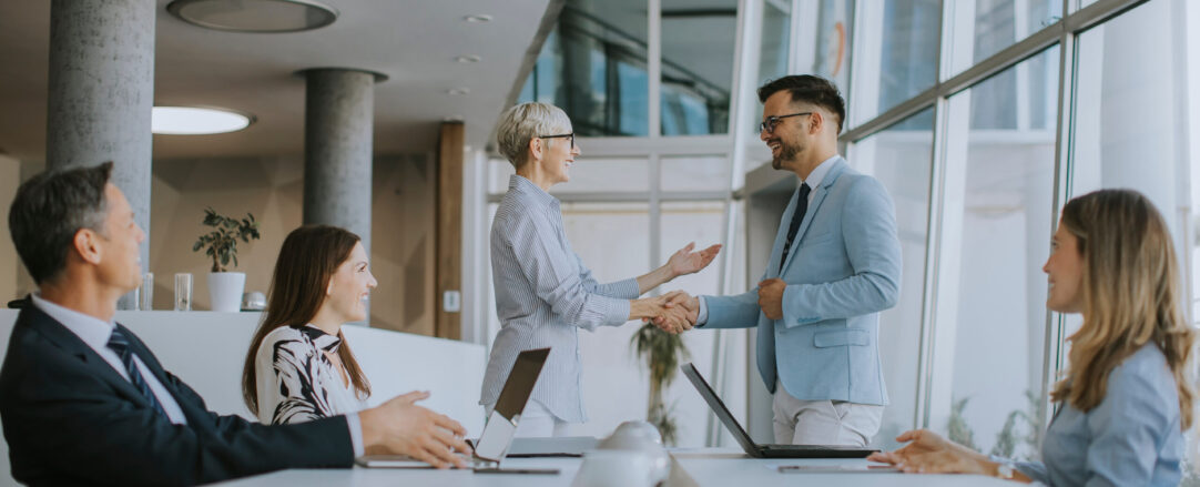 Mature business woman handshaking with young colleague on a meet