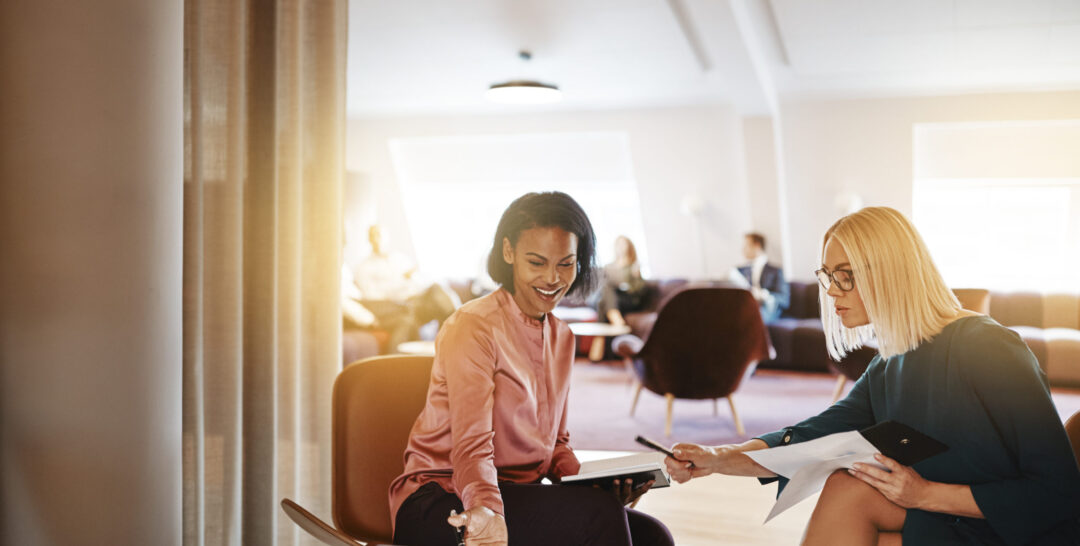 Smiling businesswomen discussing work on a laptop in an office