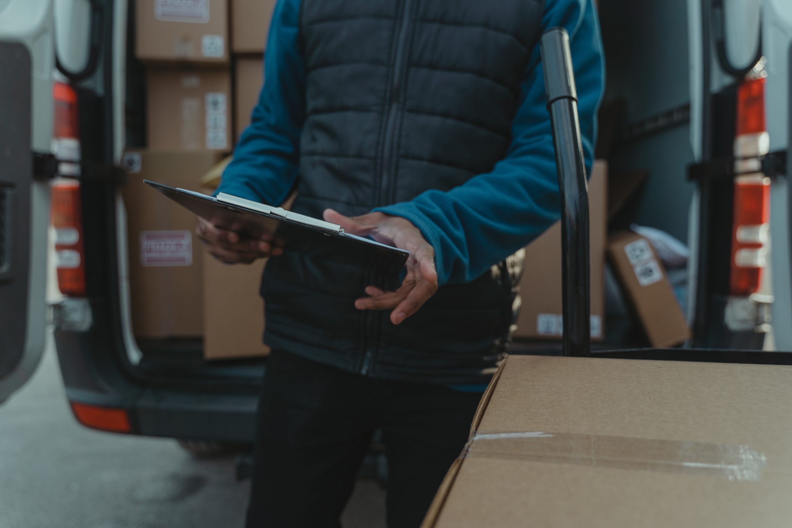 delivery man checking his clipboard in front of his delivery van